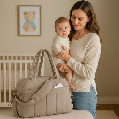 bébé dans les bras de maman près du Sac a langer